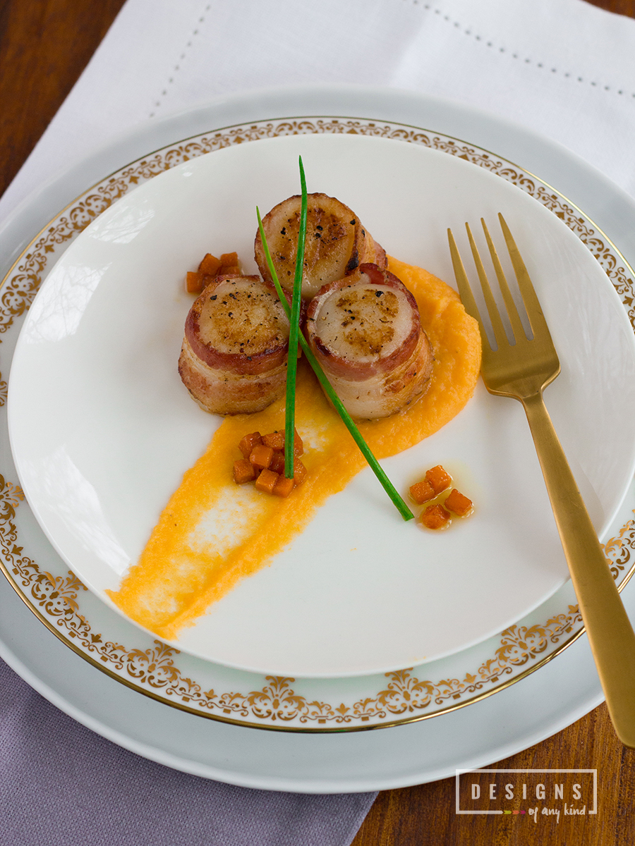 Bacon Wrapped Scallops with Truffled Butternut Squash Puree. Fresh sea scallops wrapped in bacon sit on a bed of creamy butternut squash puree with truffle butter and a garnish of candied butternut squash. A perfect way to start your Valentine's day dinner. Recipe at www.designsofanykind.com