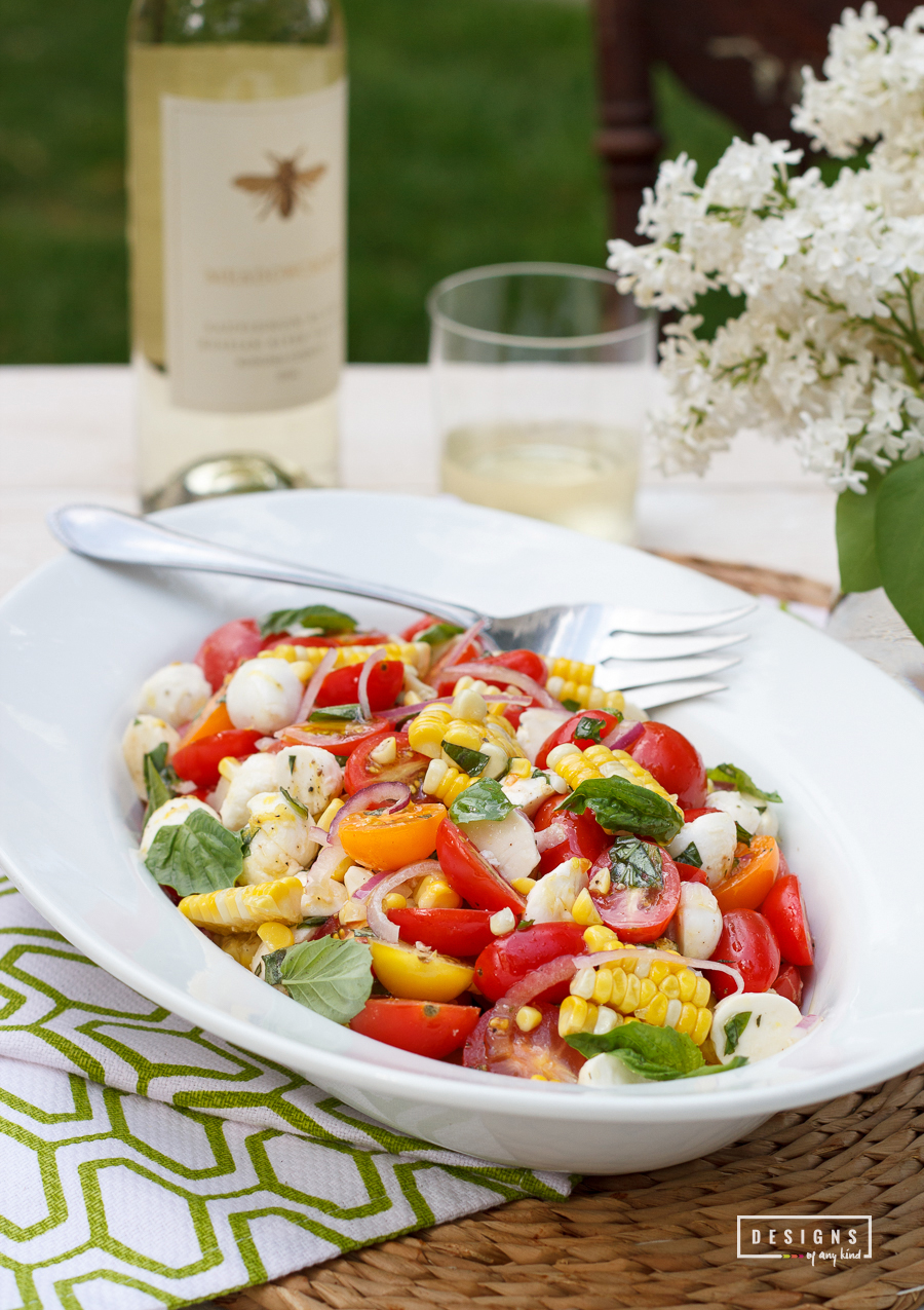 Summers are made for this "ready for entertaining" salad. Vine ripe tomatoes, grilled corn, sweet basil, a hint of lemon zest and healthy drizzle of EVOO. Perfect for your next grill out, garden party or summer potluck. Summer Tomato Salad with Grilled Corn, Mozzarella, and Basil recipe at www.designsofanykind.com