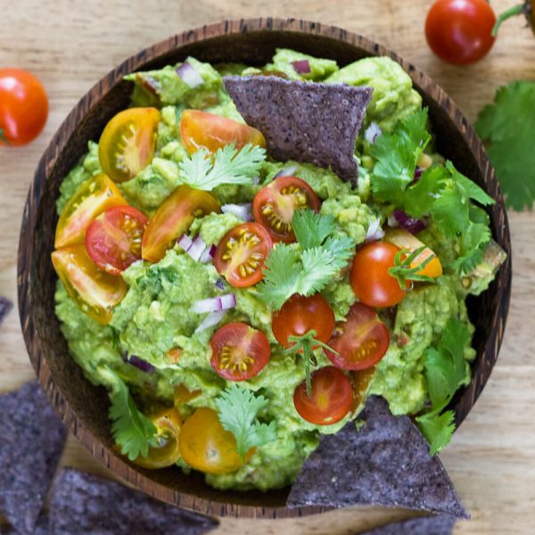 Learn how to make our favorite guacamole. Ripe avocados, garden-fresh tomatoes, lime juice, cilantro, red onions, garlic, and cumin make up the best Guacamole EVER! Recipe at www.designsofanykind.com